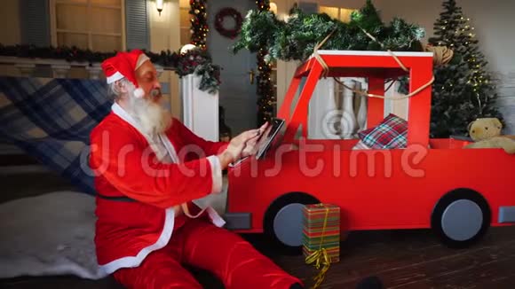 快乐的圣诞老人用平板电脑准备礼物视频的预览图
