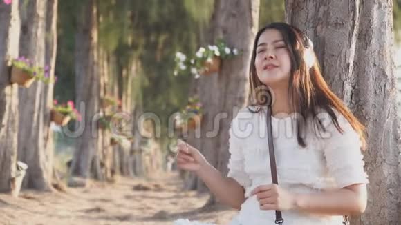 亚洲女性独自在花园里用智能手机放松视频的预览图