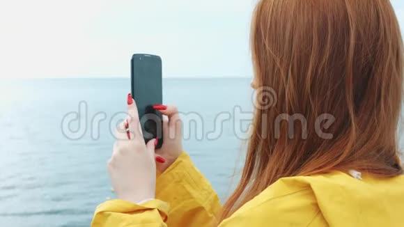 一个女人用手机摄像头拍摄美丽的海景视频的预览图
