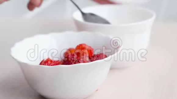 女人用勺子揉草莓把它和糖混在一起做果酱特写的手视频的预览图