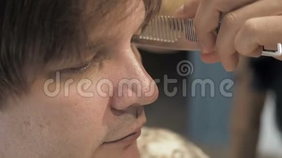 理发师在一家沙龙里给顾客剪头发和耳朵剪毛时坐在理发师扶手椅上的人视频的预览图