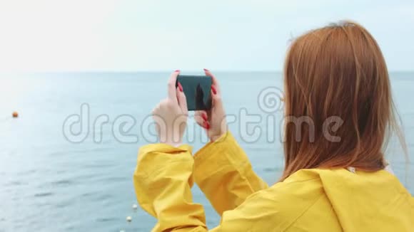 一个女人用手机摄像头拍摄美丽的海景视频的预览图