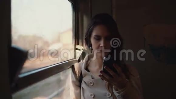 年轻女子站在火车上用智能手机有魅力的女孩和朋友聊天浏览互联网视频的预览图