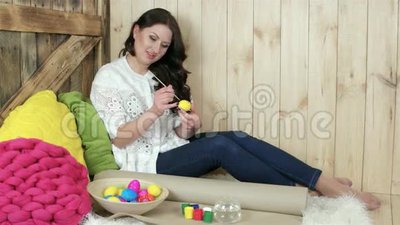 这位年轻女士展示了充满彩色鸡蛋的柳条盘子肖像装饰的复活节彩蛋视频的预览图