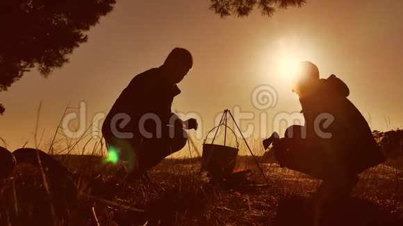 2名游客在大自然的篝火晚会露营的剪影阳光下点燃了保龄球馆的火海生活方式视频的预览图