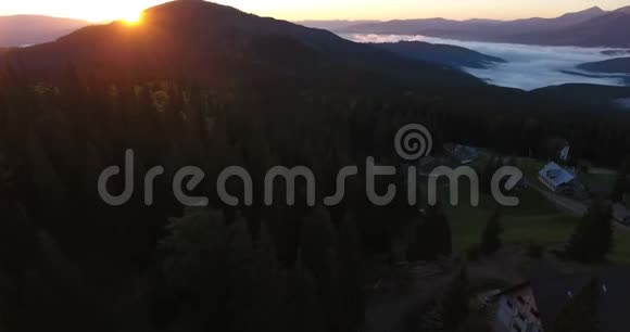 夕阳西下山中针叶林中的山村空中拍摄视频的预览图