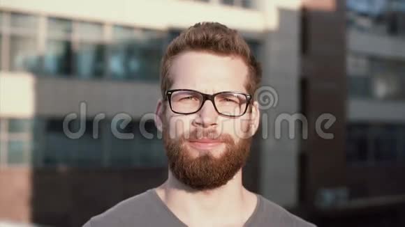 年轻严肃男子的肖像胡子和眼镜站在太阳面前链接商人站在办公室附近视频的预览图