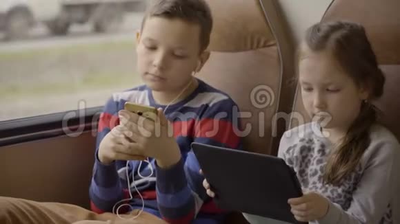 一个年轻的男孩和女孩乘坐公共汽车穿过城市使用社交网络在他们的小工具视频的预览图