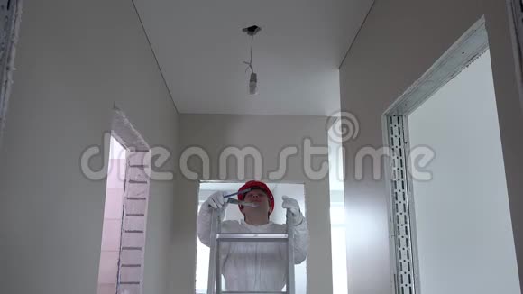戴头盔的电工爬上梯子拧开灯泡视频的预览图