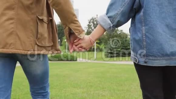 在一个城市公园里男人和女人手牵手散步的特写镜头视频的预览图