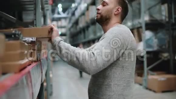 年轻人从货架上拿一个纸板箱把物品放在仓库里4K视频的预览图