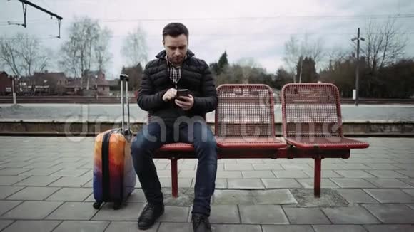 坐在火车站的年轻人在手表上等待时间视频的预览图
