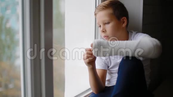 伤心的男孩断手看着窗户视频的预览图