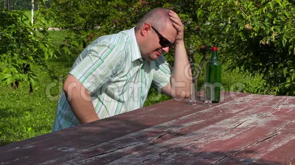 一个男人在桌上的一瓶酒附近哭泣视频的预览图