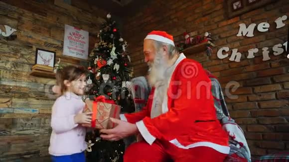 小女孩来到圣诞老人身边献上新年礼物拥抱圣诞爷爷视频的预览图