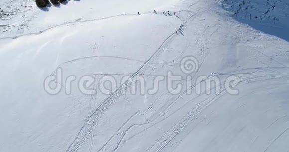 在阳光明媚的日子里人们可以在冬季雪山滑雪跑道上向后俯瞰阿尔卑斯山脉之上视频的预览图