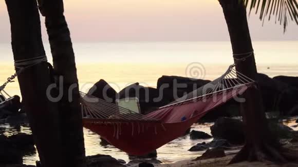 那个女人躺在海滨的红色吊床上热带岛屿上美丽的日落女人在照片上视频的预览图