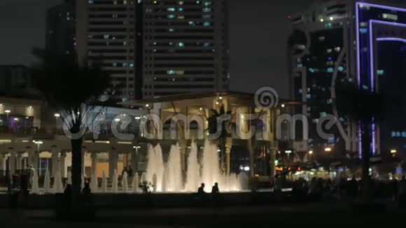 有喷泉建筑物和人的轮廓的城市夜景视频的预览图