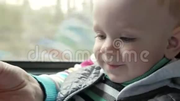 妈妈在靠近窗户的移动火车上和小儿子玩这个男孩在他母亲腿上视频的预览图