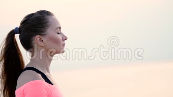 健康年轻的美丽女子冥想在海滩上练习瑜伽海边日出时放松肌肉放松心灵视频的预览图