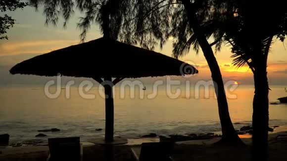 热带岛屿上美丽的日落日落时和渔夫在一起的小船从海岸看一把伞视频的预览图