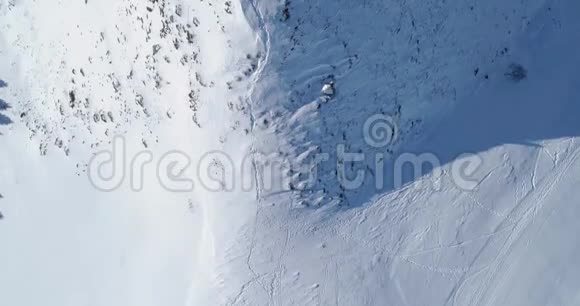 在阳光明媚的一天空中俯瞰冬季雪山滑雪场阿尔卑斯山脉之上视频的预览图