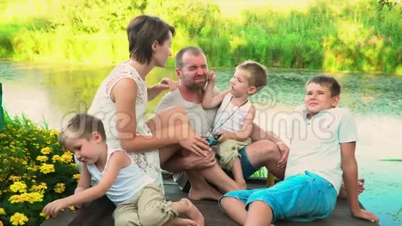 这个亲密的大家庭在湖边休息和儿子一起度假的父母慢镜头视频的预览图