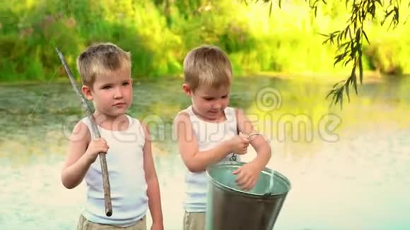 穿着白色内衣的双胞胎在相机上微笑孩子们站在池塘的码头上视频的预览图