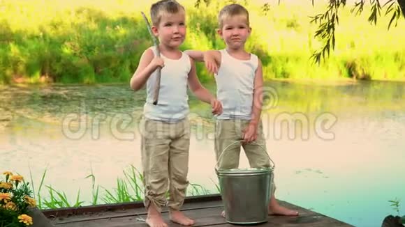 孩子们站在池塘的码头上美丽的兄弟在湖边夏日暑假视频的预览图