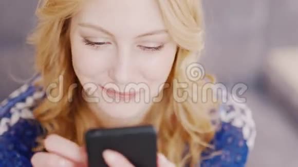 快乐的年轻女人在你的手机上读留言她快乐微笑情感反应视频的预览图