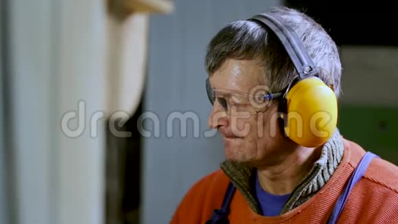 一名工人在工厂带着耳机和眼镜上班视频的预览图