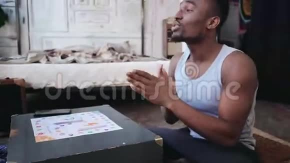 穿着睡衣的非洲帅哥扔骰子笑了多种族夫妇在地板上玩棋盘游戏视频的预览图