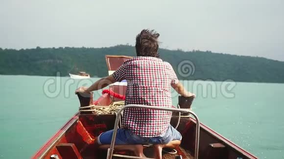 年轻男子坐在海上的木船的鼻子上动作缓慢1920x1080视频的预览图