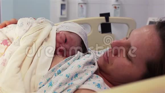 一个新生婴儿躺在医院里一位幸福的母亲的乳房上人生的第一分钟视频的预览图