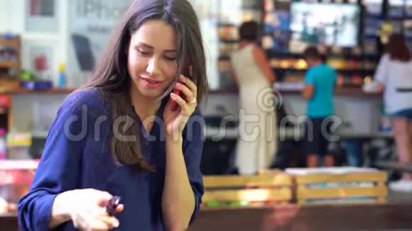 年轻的黑发女孩在街头咖啡馆用手机聊天视频的预览图