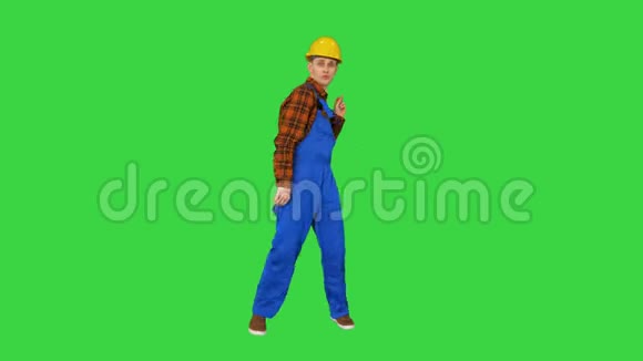 跳舞的年轻工程师与头盔后工作的绿色屏幕铬键视频的预览图