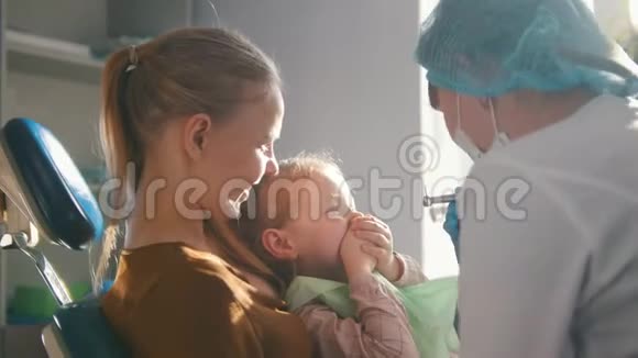 带着妈妈坐在牙医椅上的小女孩孩子在玩视频的预览图