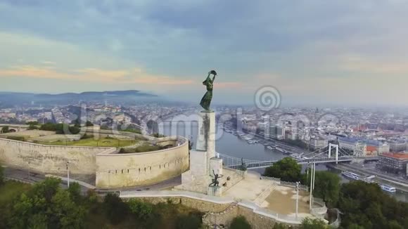 在自由女神像周围飞行背景是布达佩斯的天际线匈牙利布达佩斯4K空中镜头视频的预览图
