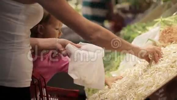 一家年轻的母亲和小女儿在超市采摘豆芽视频的预览图