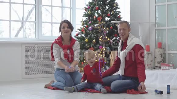 带着礼物的圣诞树背景彩纸的幸福家庭视频的预览图