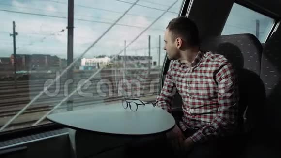 男孩看着外面的火车窗口晚上旅行4K在窗户里游泳的男孩城市景色视频的预览图