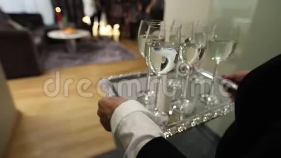 一个女人端着酒杯酒杯上放着饮料酒杯上放着香槟或水放在银盘上视频的预览图