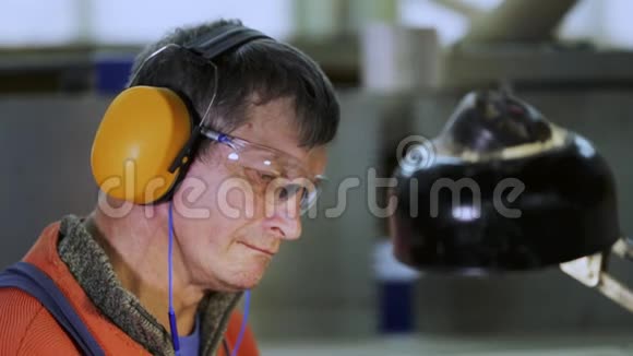 一名工人在工厂带着耳机和眼镜上班视频的预览图