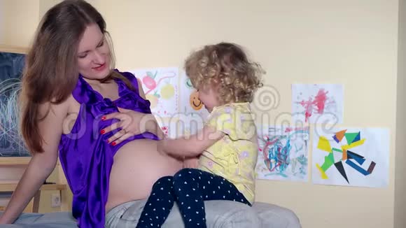 家庭女孩怀孕的母亲和蹒跚学步的女儿在肚子里照顾孩子视频的预览图