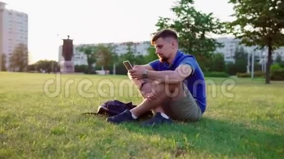 一个人坐在草地上翻着智能手机视频的预览图