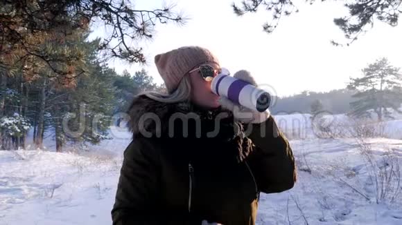 在户外冬天的森林里喝热茶或咖啡的年轻女子视频的预览图