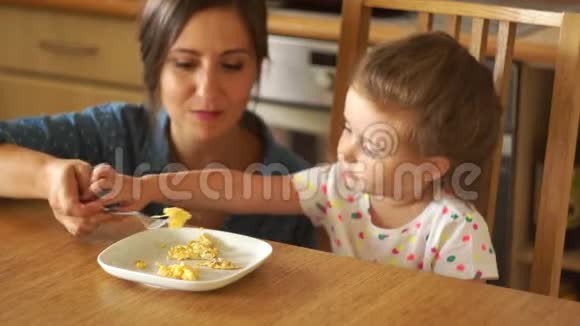 一个小女孩正在厨房里喂妈妈他玩食物把它放在桌子上视频的预览图