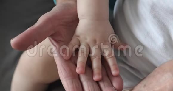 老皱的手摸着婴儿柔软的手视频的预览图