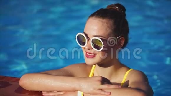 夏天一个戴着墨镜的成年女孩在室外游泳池游泳视频的预览图