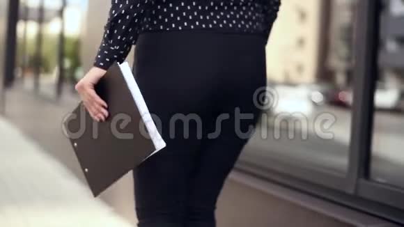 漂亮的女商人手里拿着文件走在办公楼旁边视频的预览图